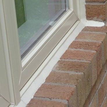 Fresh caulking on exterior window, brick facade